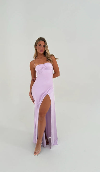 Hntr the Label Gaia Gown Lilac. Model standing in front of a white wall with arm crossed behind her back. 