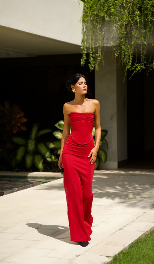 Hntr the Label Louie Gown two piece set in Wine which is a dark red. Model is walking on pavers with her head turned away from the camera. 